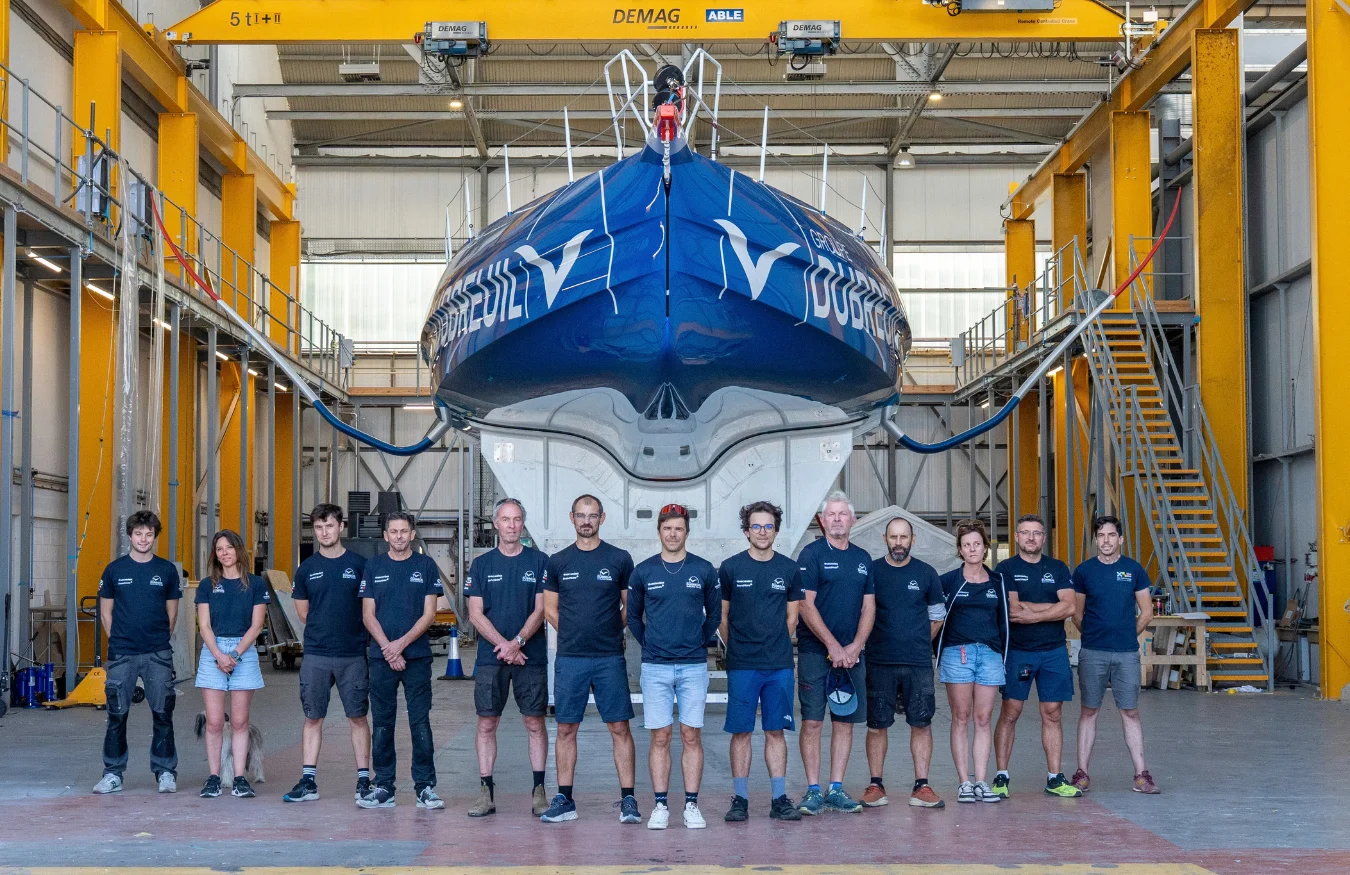 La Groupe Dubreuil Sailing Team pose fièrement face devant l'IMOCA avant sa première sortie du hangar