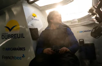 Sébastien Simon, à l'intérieur de son cockpit, regarde par le hublot sous un soleil couchant