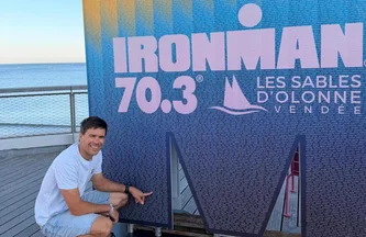 Sébastien Simon pose devant l'affiche de l'Ironman des Sables-d'Olonne 2026