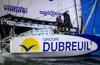 Sébastien Simon à l'arrivée du Vendée Globe 24/25 fait le signe trois depuis le pont de son bateau avec ses doigts en référence à sa troisième place