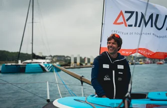 Sébastien Simon souriant devant le drapeau Défi Azimut accroché à l'arrière de son IMOCA