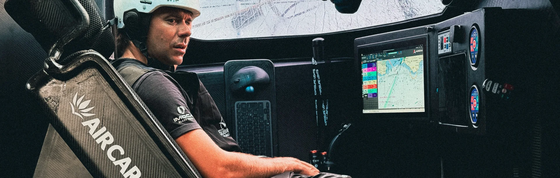 Sébastien Simon est à l'intérieur du cockpit de l'IMOCA Groupe Dubreuil 2, assis dans son siège de veille.