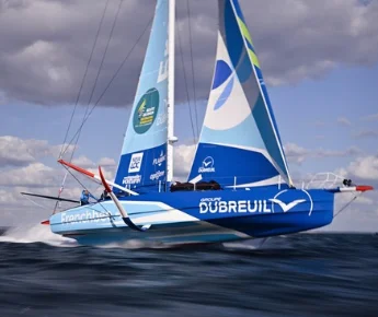 L'IMOCA Groupe Dubreuil 2 s'élève au-dessus de l'eau sur ses foils en soulevant des gerbes d'écume.